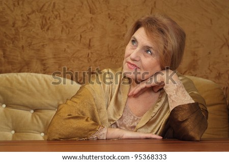 good old woman sitting on a sofa on a brown background