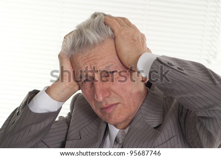 an old man holding his head on a light background