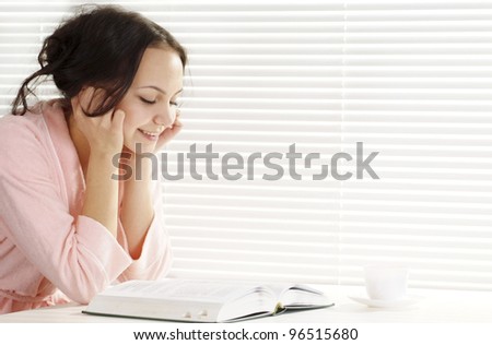 happy girl with a book sits on a white background