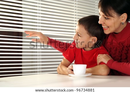 Mother and son looking out the window on a light background
