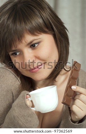 Nice beautiful woman holds in one hand and a cup of chocolate in the other