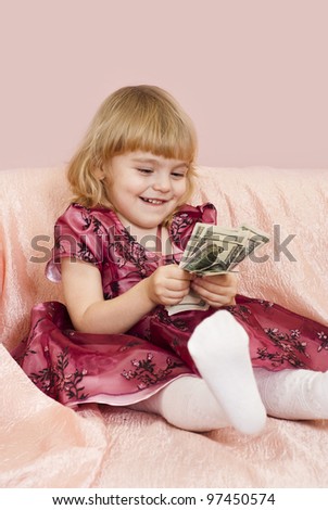 Beautiful little girl finds the money on a pink background