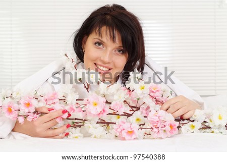 Beautiful female lying in bed under a blanket of flowers