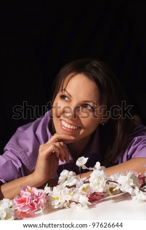 Portrait of a nice charming woman in a shirt in the flower is on a black background