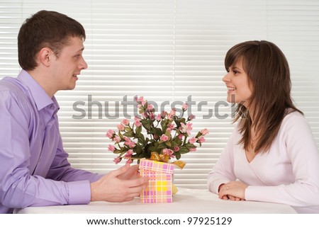 Happy Caucasian guy and his girlfriend are sitting at a table in a cafe
