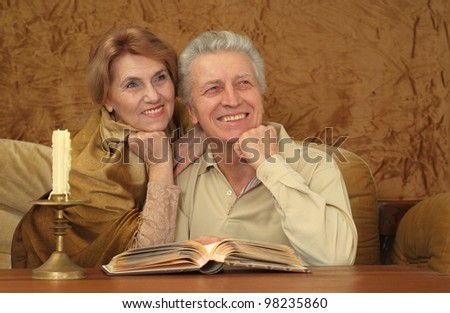 Beautiful Caucasian happy couple of old people sitting on a brown background