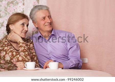 A beautiful pair of pensioner people sitting together on a pink background