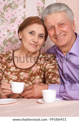 A beautiful pair of elderly people sitting together on a pink background