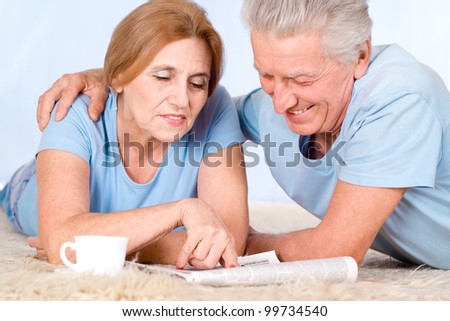 happy old couple with newspaper on carpet