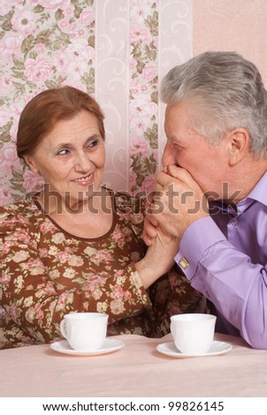 A beautiful pair of aged people sitting together on a pink background