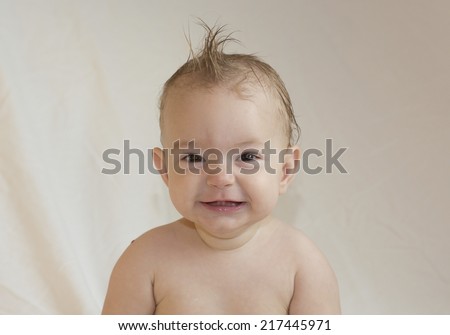 smiling baby with spiky hair, looking at camera with a neutral background