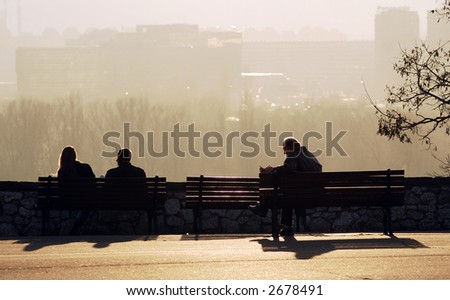 Young couple and older man sittin on bench in park