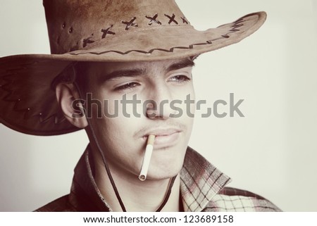 Artistic portrait of the young beautiful man. The young man smokes a cigar