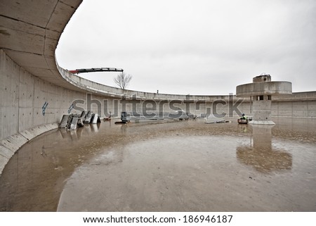 Huge concrete circular sedimentation tank Water settling, purification in the water station. Man sitting under the pillar. As an umbrella