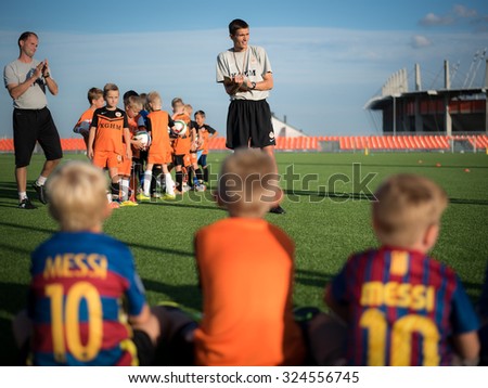 LUBIN, POLAND - SEPTEMBER 18; 2015: Trainer verifies the presence before training at Football Academy KGHM Zaglebie. Two boys wearing Messi T-shirt at first plan.