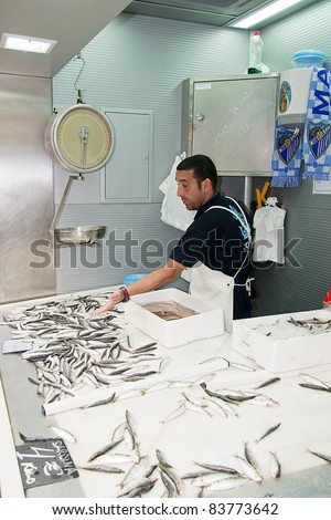 MALAGA, SPAIN - JUNE 10: An unidentified seller packs the fishes at his shop in the popular central market on June 10, 2011 in Malaga, Spain.It was renovated in 2010 and it was reopened on March 2011.