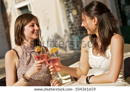 Two Young Women Cheering with Cold Drinks,Italy