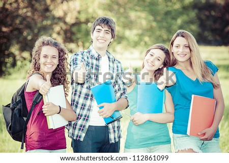 Young group of happy students showing thumbs up sign together outdoor in the park
