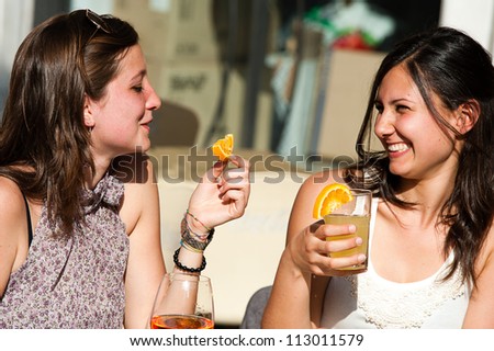 Two Young Women Cheering with Cold Drinks,Italy