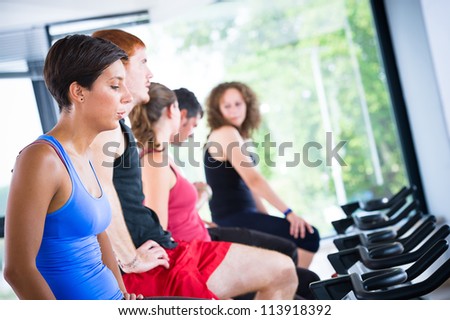 Five people tired in the gym, exercising their legs doing cardio training ,Italy