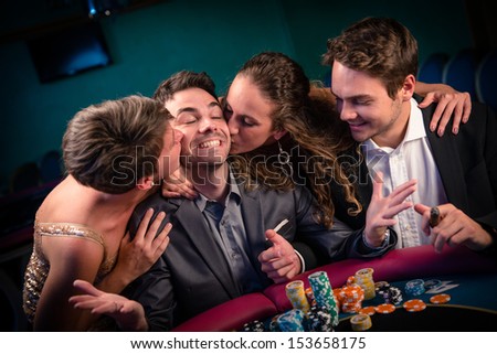 Man with glamorous women in casino at poker table