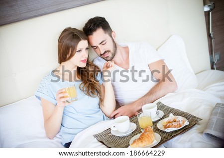 Happy man and woman having luxury hotel breakfast in bed together-stock