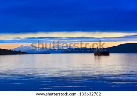 Boat (bulk carrier) on the fjords of Norway, mountain in the background with sunset light.