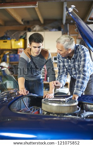father and son working together on a classic car in a garage