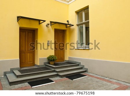 Entrance to yellow home - two brown metal doors and window