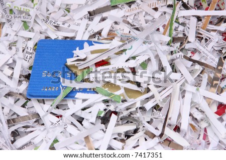Shredded documents cover an exposed portion of a credit card.