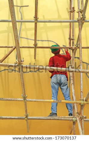 Worker working during renovation of big buddha statue at Wat Muang, Thailand.