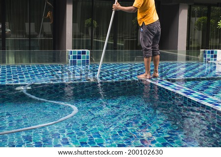 Man cleaning the swimming pool with vacuum cleaner