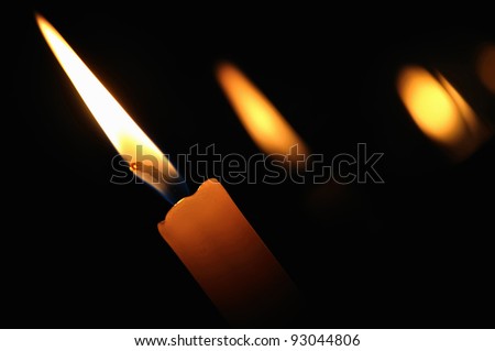 A burning candle in the church on a dark background
