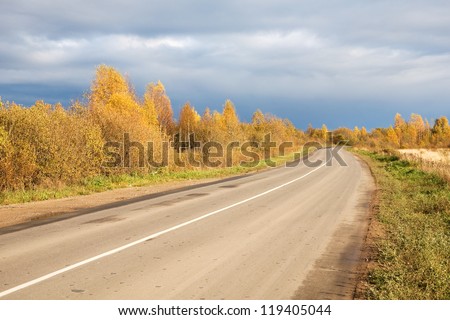 Dirt paved road in the Russian north. Autumn forest.