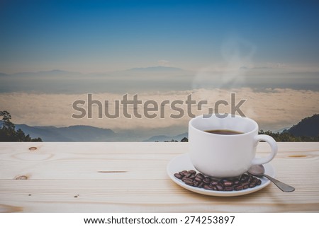 Morning cup of coffee with mountain background at cloud .vintage color tone