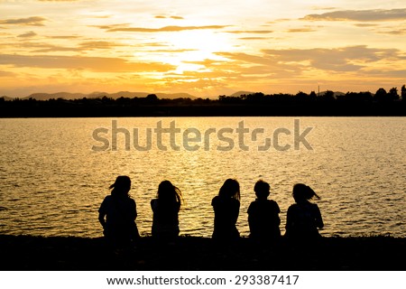 Silhouette Of Friends Sitting On Beach during sunrise time