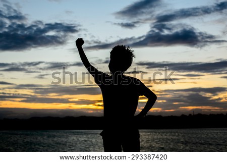 Man with his hand up watching the sun set