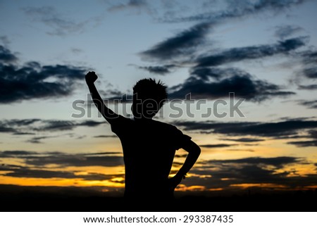 Man with his hand up watching the sun set