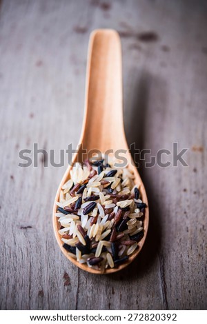 Rice in wood spoons on wood background