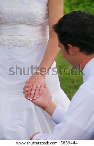 A young groom holding his new wife\'s hand. The focus is on the ring, not the groom.