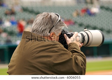 A photographer capturing an image at a baseball game.