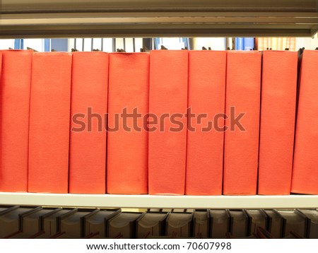 stack of books in red binding on a library shelf
