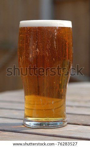 Pint of refreshing ale on table in pub beer garden table