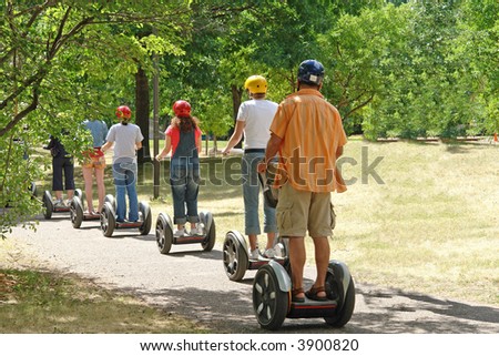 A picture of scooter riders cruising thought park on nice day