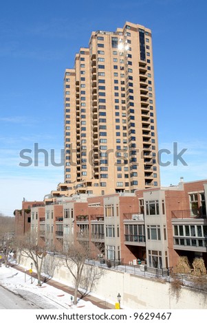 A picture of a residential skyscraper standing above a row of apartments