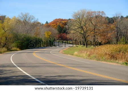 A picture of winding country road curving through autumn trees