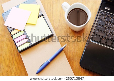 note book and black coffee on wooden table with post it