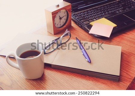 note book and laptop on wooden table with retro filter effect
