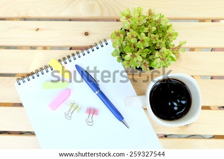 note book and office tools on the wood table with black coffee