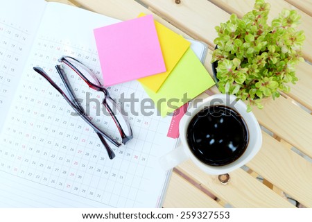 planner book and office tools on the wood table with black coffee